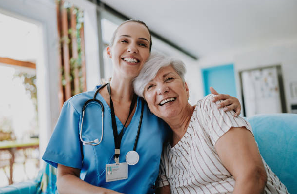 A healthcare worker smiling alongside an older woman